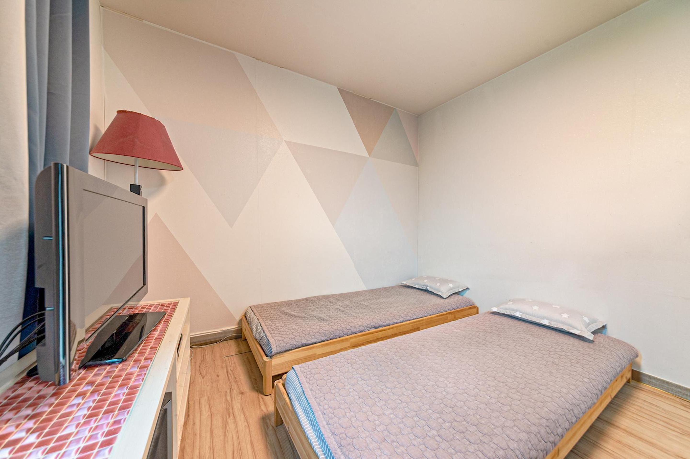 A room with two single beds, a desk with a computer, and a TV.