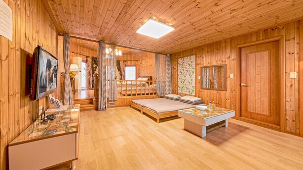 A wooden cabin interior with a bed, a desk, and a bathroom. - Gangnueng Gadunji Pension (Gangneung)