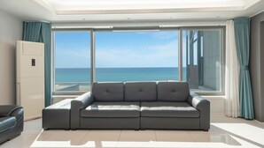 A modern living room with a large window offering a view of the ocean. - Gangneung Badauibyeol Pension (Gangneung)