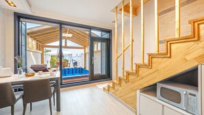 Eine moderne Küche mit Mikrowelle, ein Essbereich mit Tisch und Stühlen sowie eine große Schiebeglasdoor zum Außenbereich.