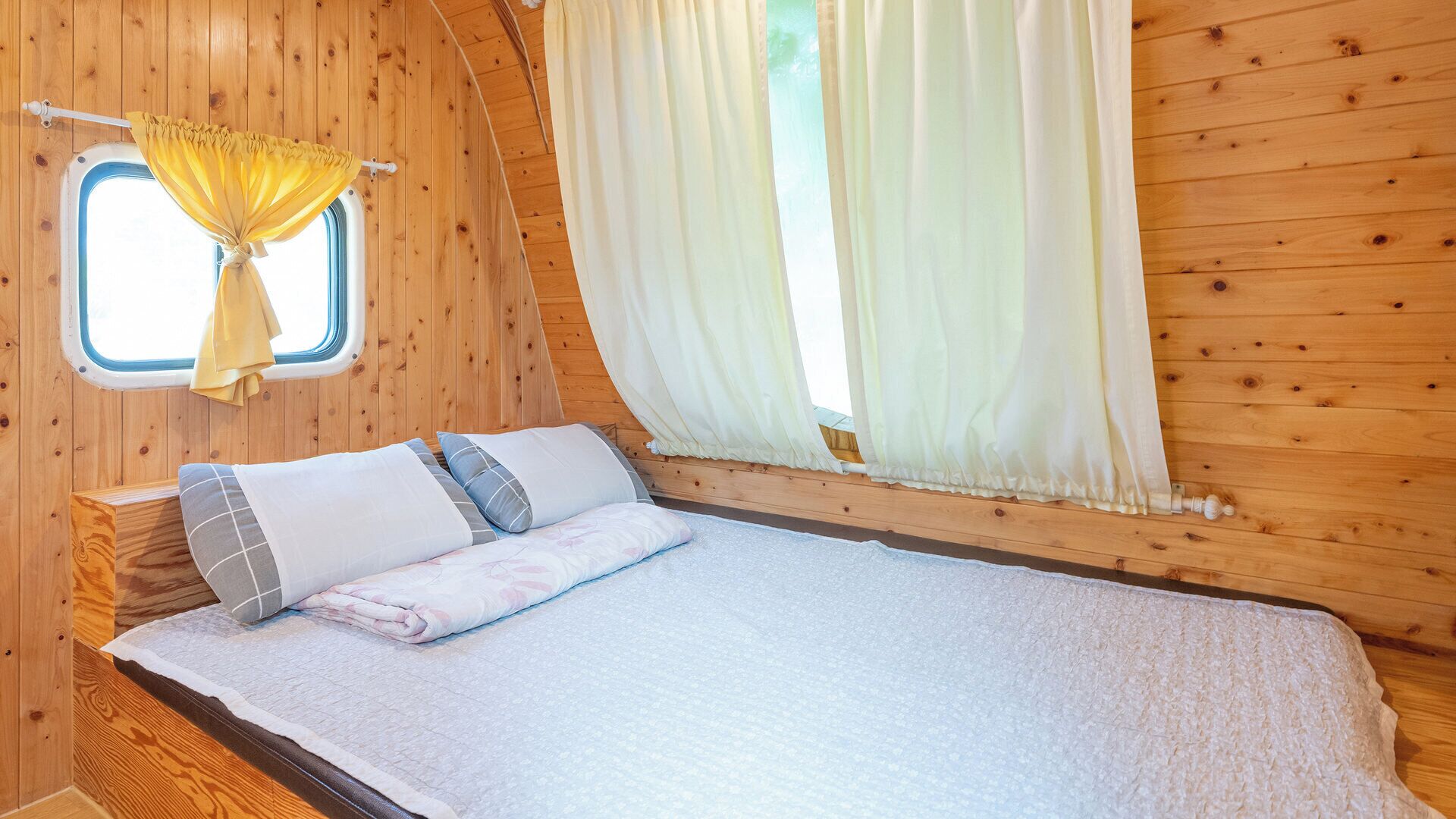 A cozy cabin bedroom with a bed, curtains, and a window.