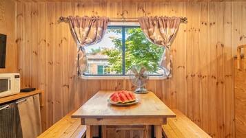 Quarto de cabana de madeira com uma mesa de madeira, micro-ondas e ventoinha.