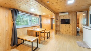 Un intérieur en bois comprenant un coin repas, un téléviseur et une cuisine.