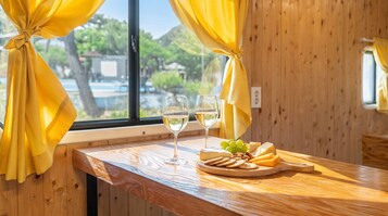 A wooden table with a cheese board, grapes, nuts, and two glasses of white wine.