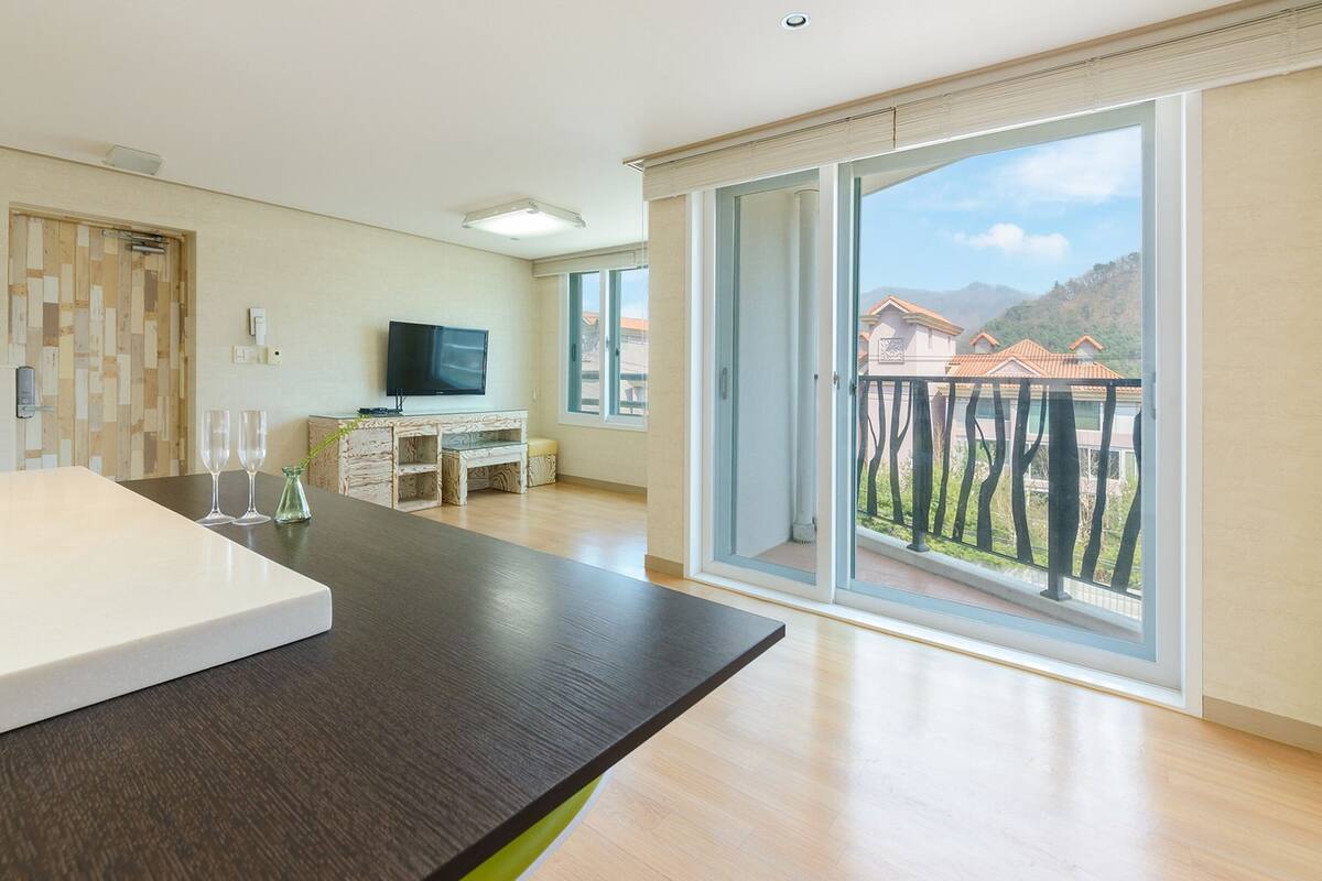 Een moderne kamer met een groot raam, een flatscreen televisie en een houten kast.