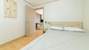 Een slaapkamer met een bed, een houten hoofdbord, een deur en een kleine tafel met een vaas.