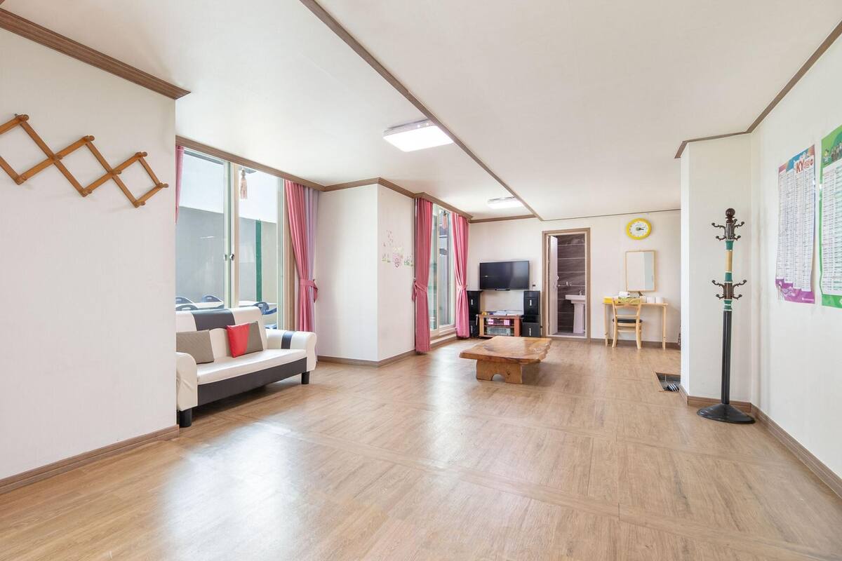 A spacious room with a sofa, a wooden coffee table, and a television.
