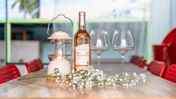 Una mesa con una botella de vino, dos copas, un farol y flores blancas.