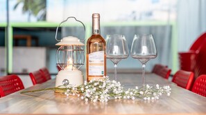 Une table avec une bouteille de vin, deux verres, une lanterne et des fleurs blanches.