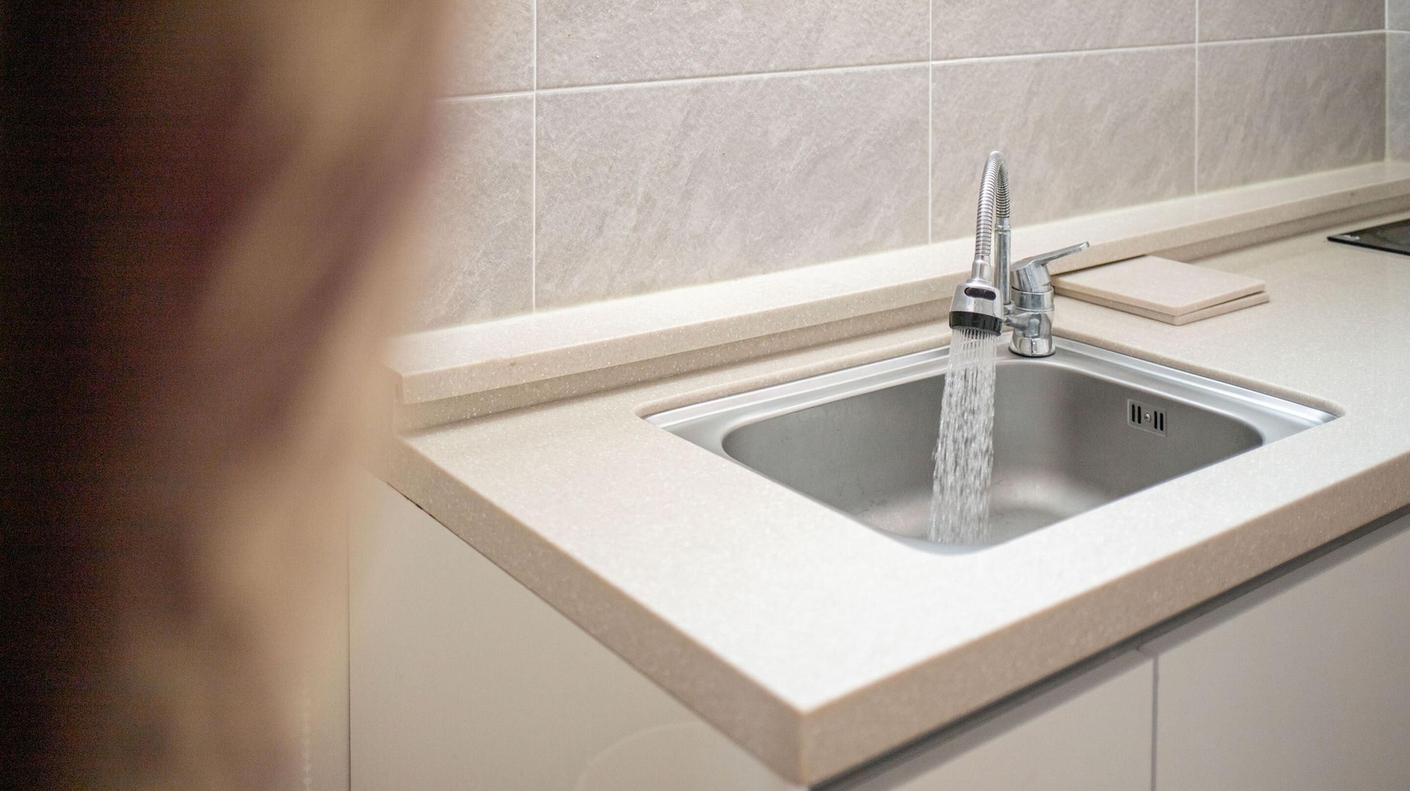 A kitchen sink with a modern faucet, a soap dish, and a countertop.