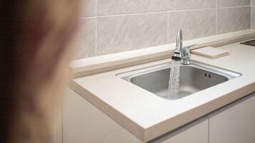 A kitchen sink with a modern faucet, a soap dish, and a countertop.