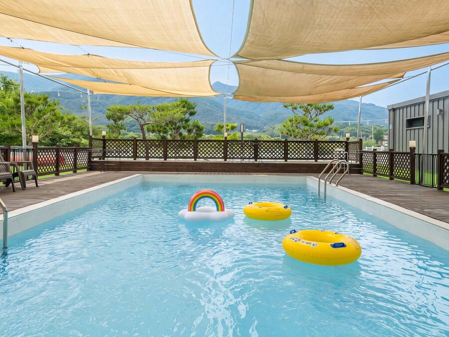A pool with floating rings, a lifeguard chair, and a view of mountains.