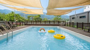 A pool with floating rings, a lifeguard chair, and a view of mountains. - Gapyeong Dangdangi Pet Poolvilla Blue (Gapyeong)