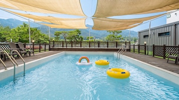 Piscina con flotadores, una silla de salvavidas y vistas a las montañas.