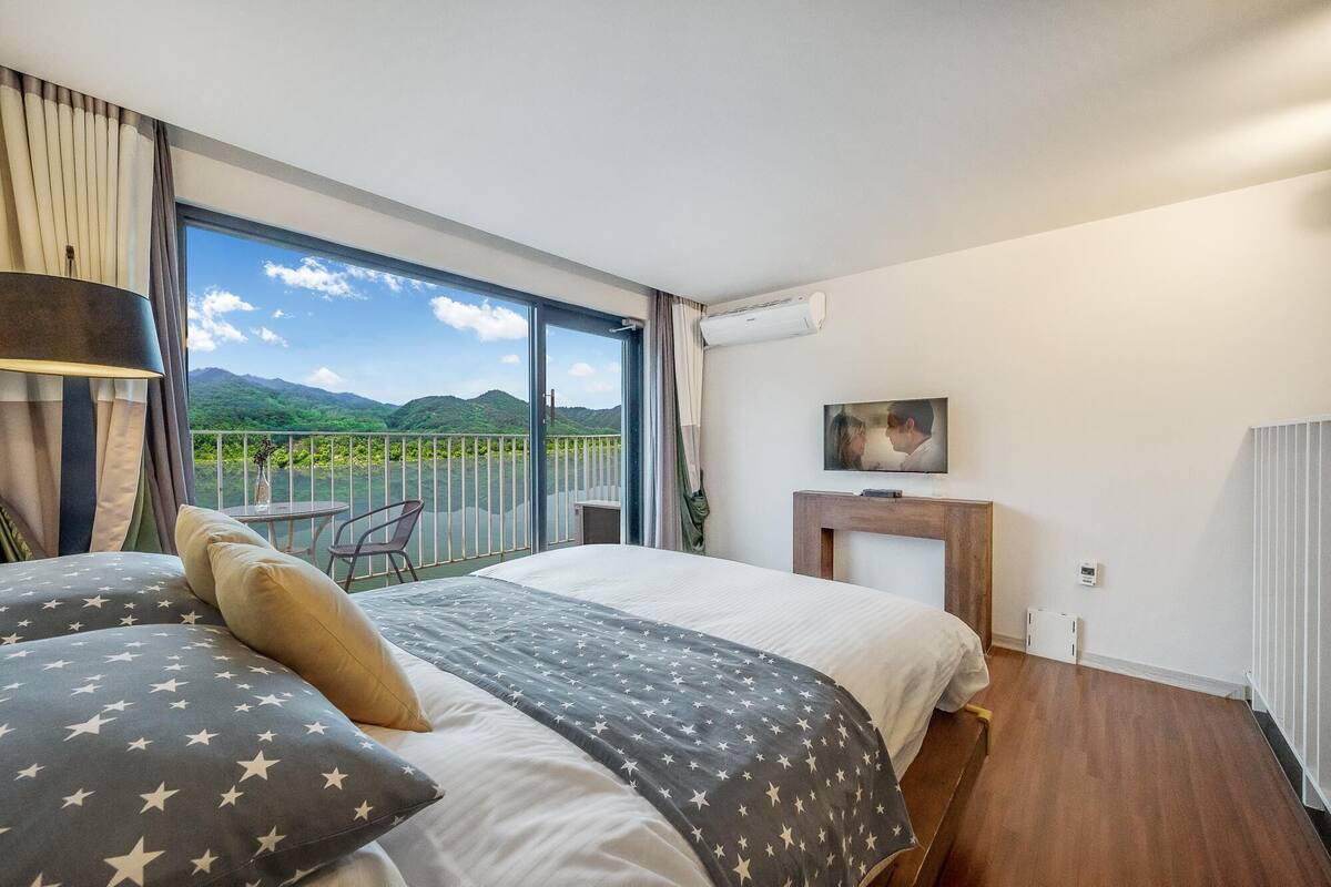 Une chambre d’hôtel avec un grand lit, une télévision, une cheminée et un balcon offrant une vue sur les montagnes.