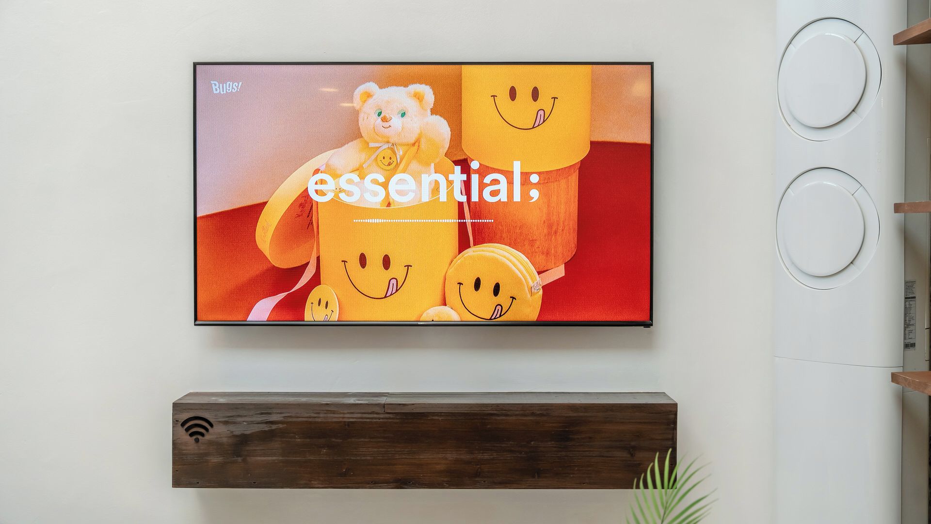 Un televisor montado en la pared con un estante de madera debajo.