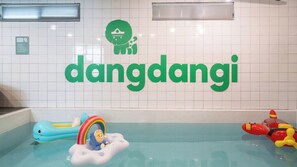 A swimming pool area with a large green sign reading 'dandangji' and a small inflatable toy with a rainbow. - Gapyeong Dangdangi Pet Poolvilla Blue (Gapyeong)