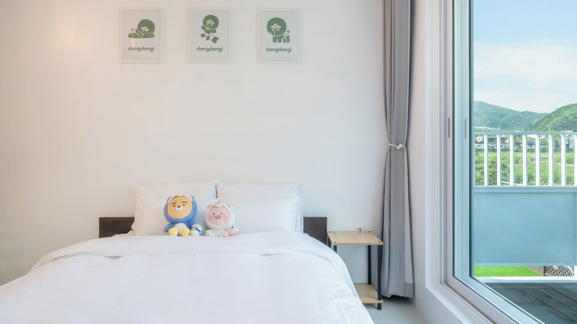 A bedroom with a bed, pillows, a nightstand, and a window with a view of greenery.