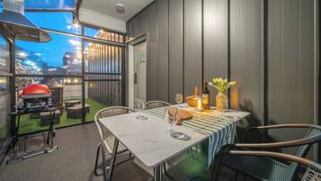 Un área de comedor al aire libre con una mesa para dos, una parrilla y vistas de la ciudad.