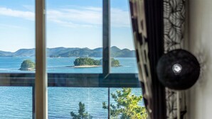 Une pièce dotée d’une grande fenêtre donnant sur une étendue d’eau, avec des îles et des montagnes visibles au loin.