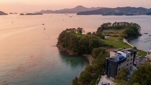 Une propriété située sur la côte, offrant une vue sur la mer, dotée d’une piscine et comprenant un bâtiment moderne avec un toit plat.