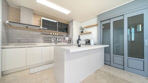 Une cuisine moderne dotée d’un îlot central, de meubles de couleur grise et d’un four encastré.