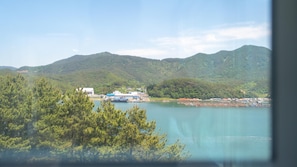 Una zona costera con una extensa masa de agua, un barco anclado en un muelle y un paisaje montañoso al fondo.