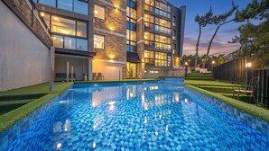 Un bâtiment moderne doté d’une piscine, d’un espace extérieur aménagé et d’un jardin bien entretenu.