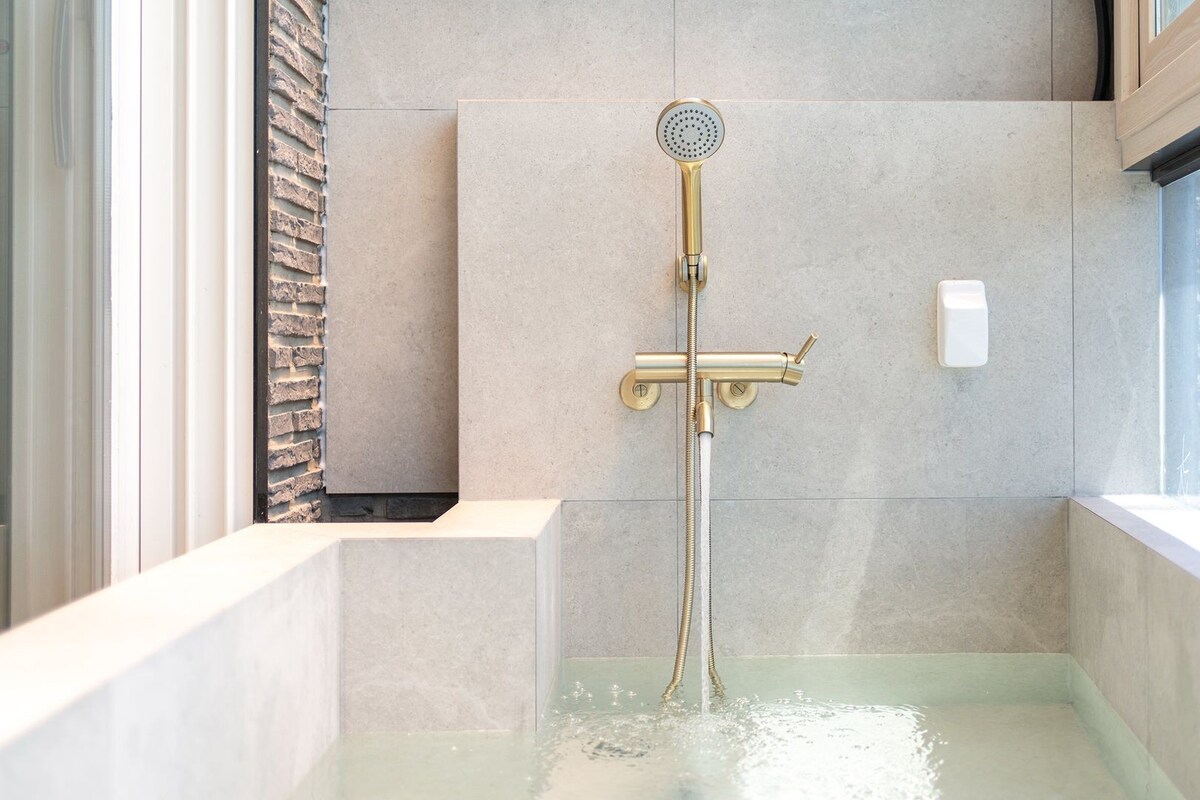 Une douche moderne dotée d’un pommeau de douche à main, d’un panneau de commande et d’un espace clos en verre.