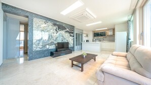 Una sala de estar moderna con una pared de mármol, un sofá, una mesa de centro y un televisor.