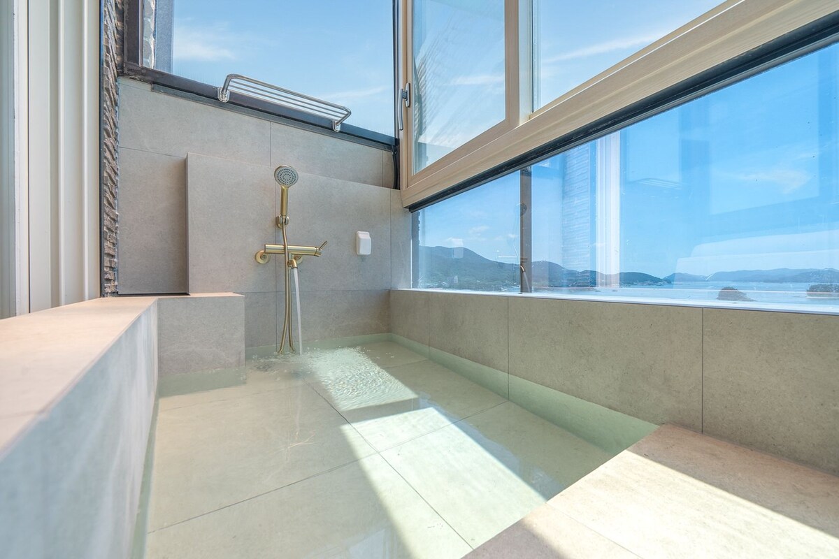 Une salle de bain moderne dotée d’une douche à parois de verre, de toilettes intégrées et offrant une vue sur un plan d’eau.