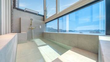 Un baño moderno con cabina de ducha de vidrio, inodoro empotrado y vistas a una masa de agua.