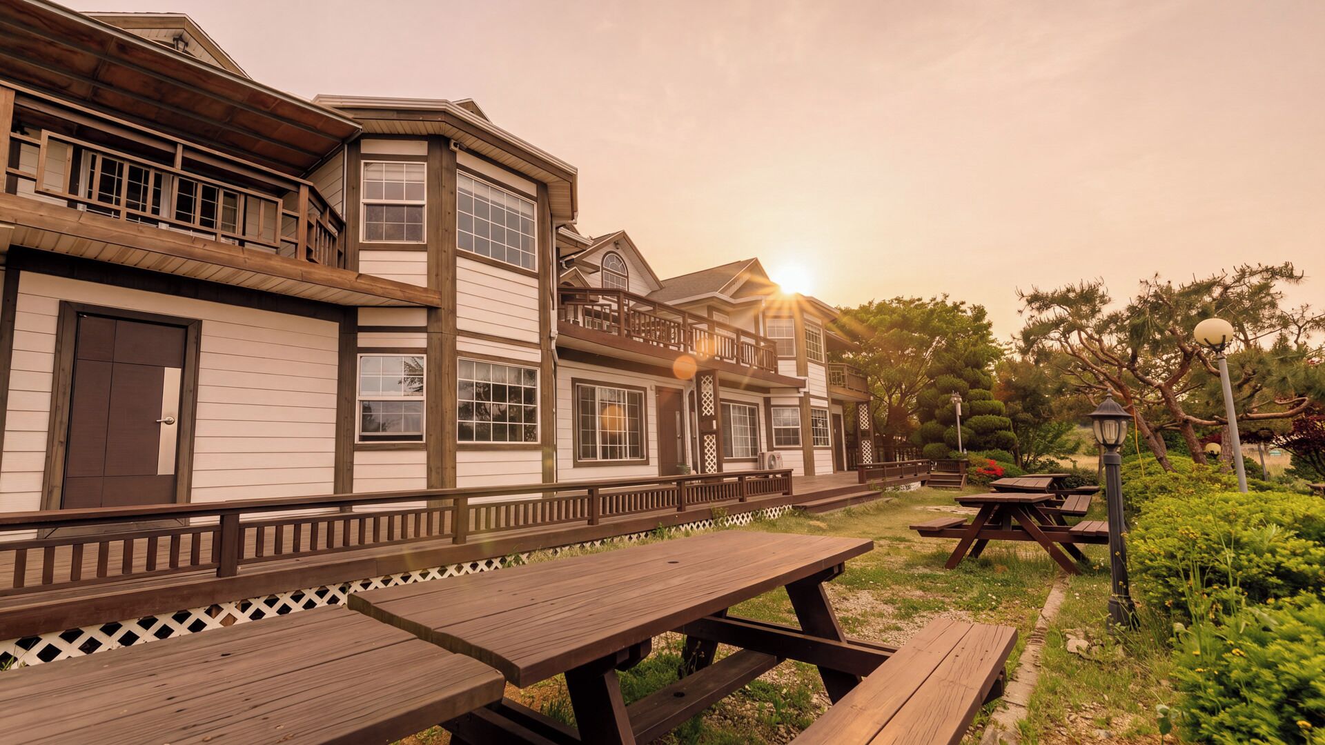 A two-story building with a balcony, wooden deck, and picnic tables.
