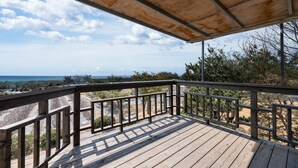 A wooden deck with a metal railing overlooking a beach and ocean. - Ganghwa Western Beach Pension (Incheon)