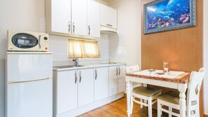 A kitchen with white cabinets, a microwave, a sink, and a dining table with chairs. - Gapyeong Elin Pension (Gapyeong)