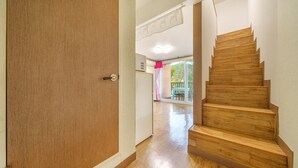 Eine Holztreppe führt zu einem Raum mit einer Schiebeglastür.