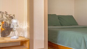 A room with a bed, a bedside table with a lamp, and a wall with a painting.