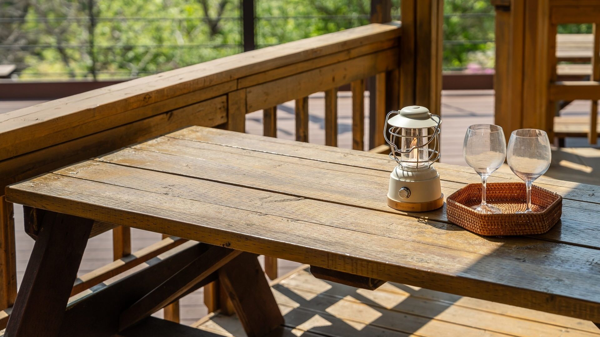 Een houten tafel met een draagbare kachel en twee glazen op een geweven dienblad.