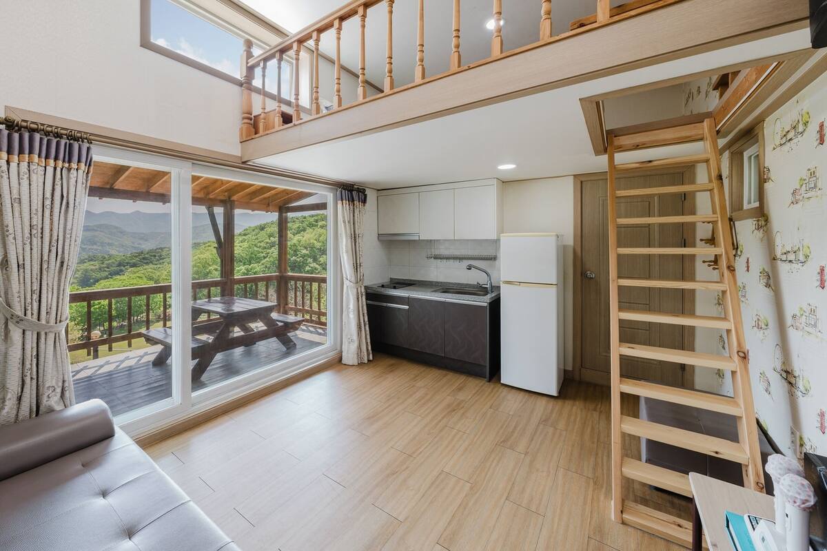 A compact living space with a balcony, a kitchenette, and a sofa.