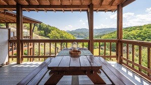 Una terraza de madera con una mesa de picnic y vistas a un paisaje montañoso.