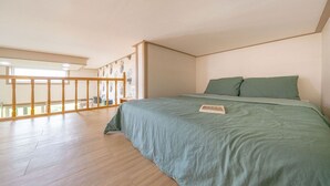 A bedroom with a large bed, a wooden floor, a balcony with a railing, and a view of the outdoors. - Gapyeong Art Pension (Gapyeong)