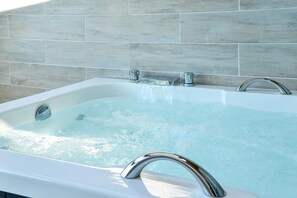 A modern bathroom with a bathtub, chrome faucets, and a tiled wall. - Gangneung 2block Pension (Gangneung)
