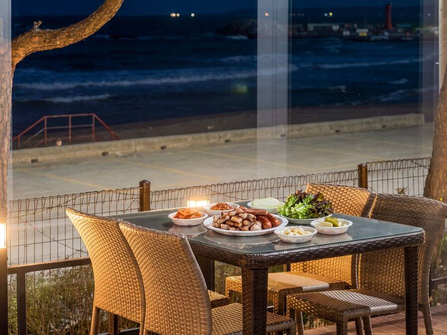 A dining table with chairs and a view of the ocean at night.