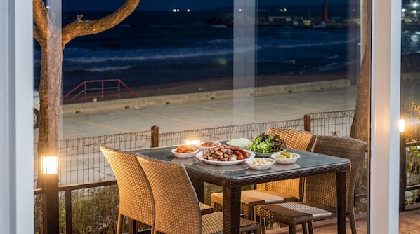Una mesa de comedor con sillas y vista al océano de noche.