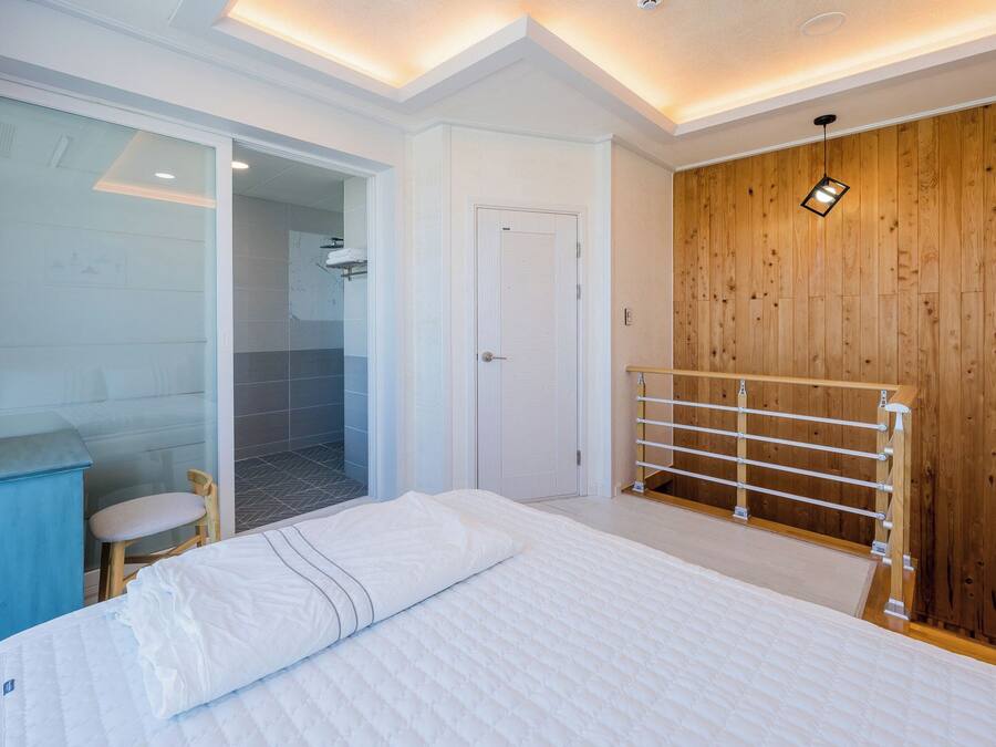 Un dormitorio moderno con una cama, un armario de madera, una cabina de ducha de vidrio y una mesita de noche azul.