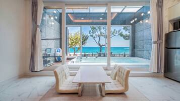 A modern interior with a large sliding glass door leading to a pool area with a view of the sea.