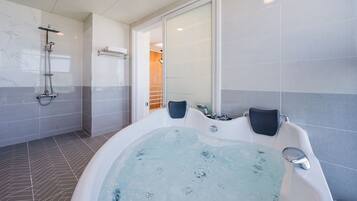 A modern bathroom with a large bathtub, a shower area, and a glass-enclosed walk-in shower.