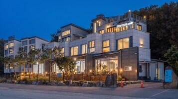 Un hotel de varios pisos con un letrero de Play Beach, ventanas amplias y una entrada bien iluminada.