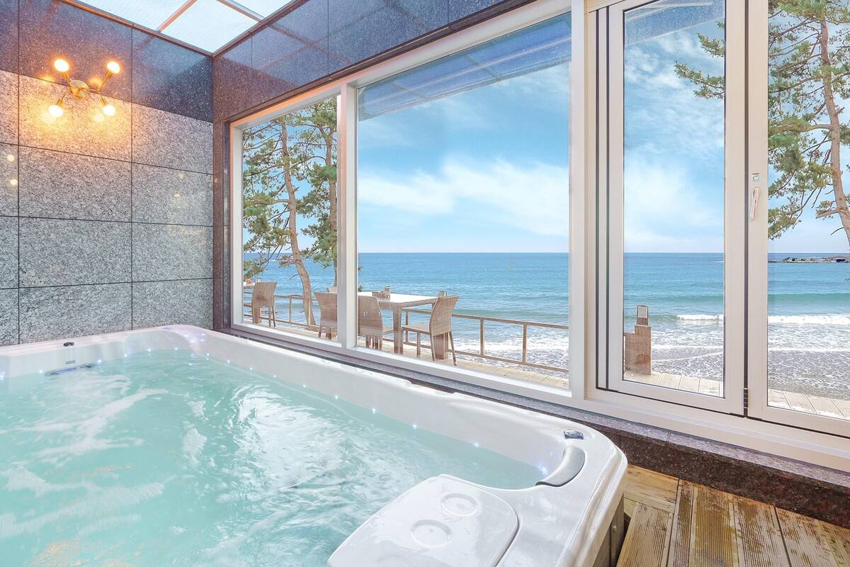 Ett spaområde med ett bubbelbad, utsikt över havet och en sittgrupp med bord och stolar.