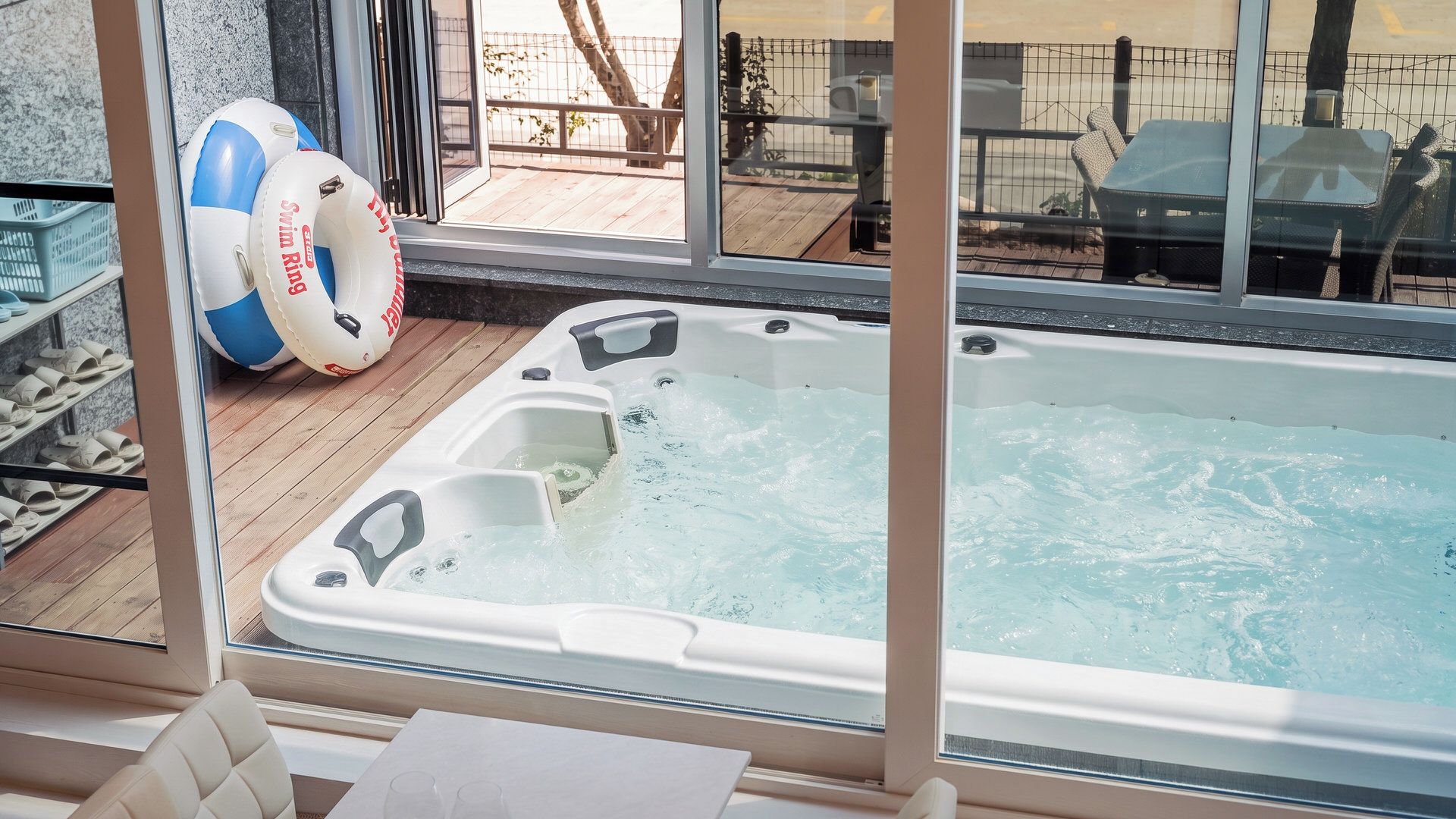 A hot tub with a wooden deck and a view of a fenced outdoor area.